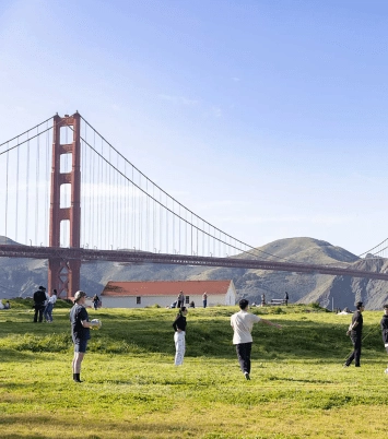 View of the Golden Gate Bridge with people playing soccer at Crissy Field.