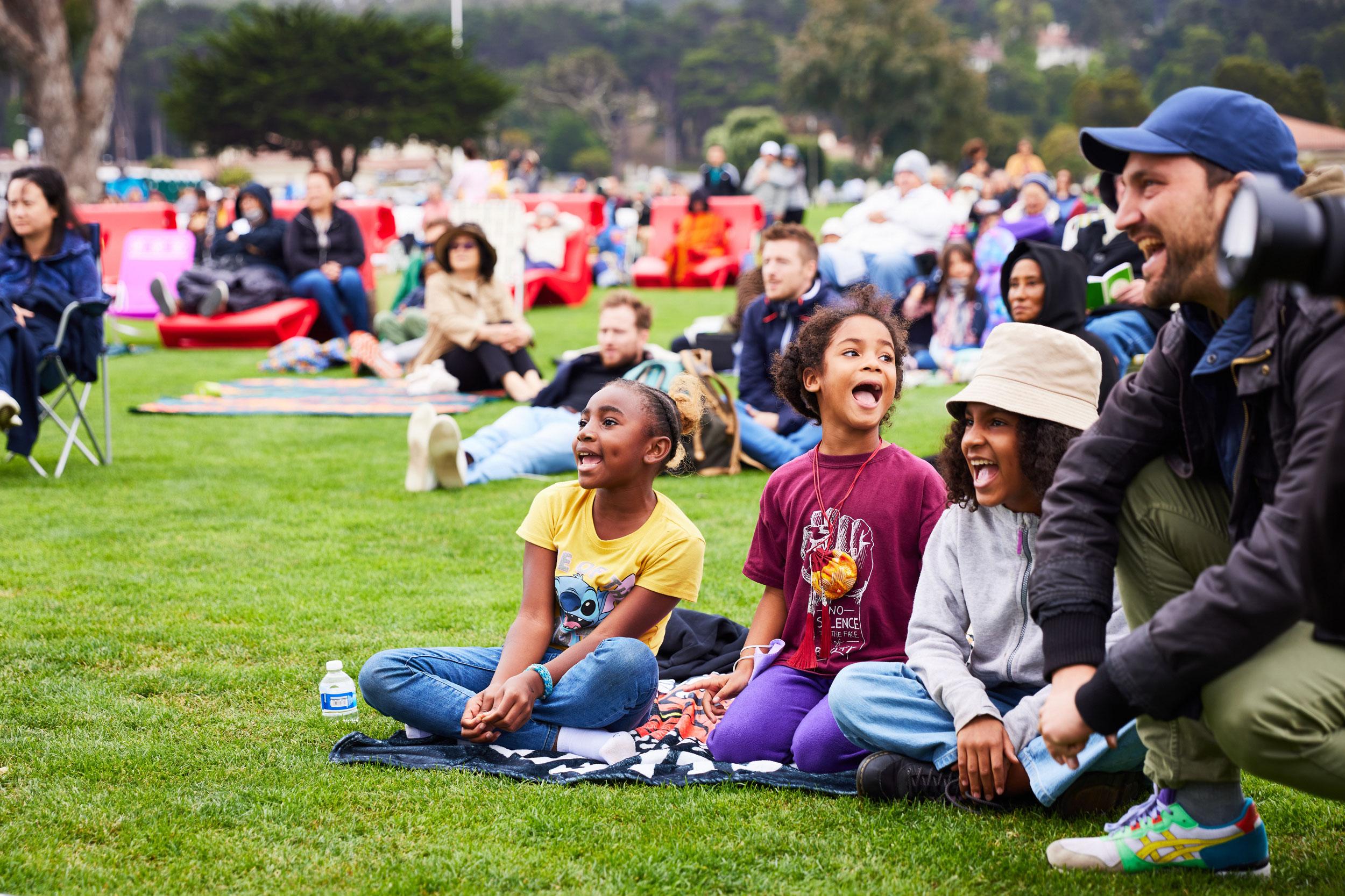 Kids and adults on picnic blankets and chairs on Main Parade Lawn