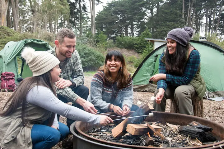 Four people making smores at a fire pit at Rob Hill Campground in the Presidio of San Francisco.