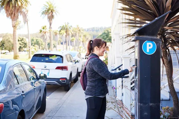 A woman pays for parking at a Pay-and-Display machine.