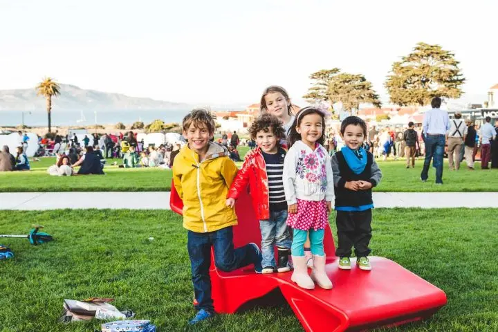 A group of kids standing on a red Share Chair on the Main Parade Lawn. Photo by Rachel Styer.