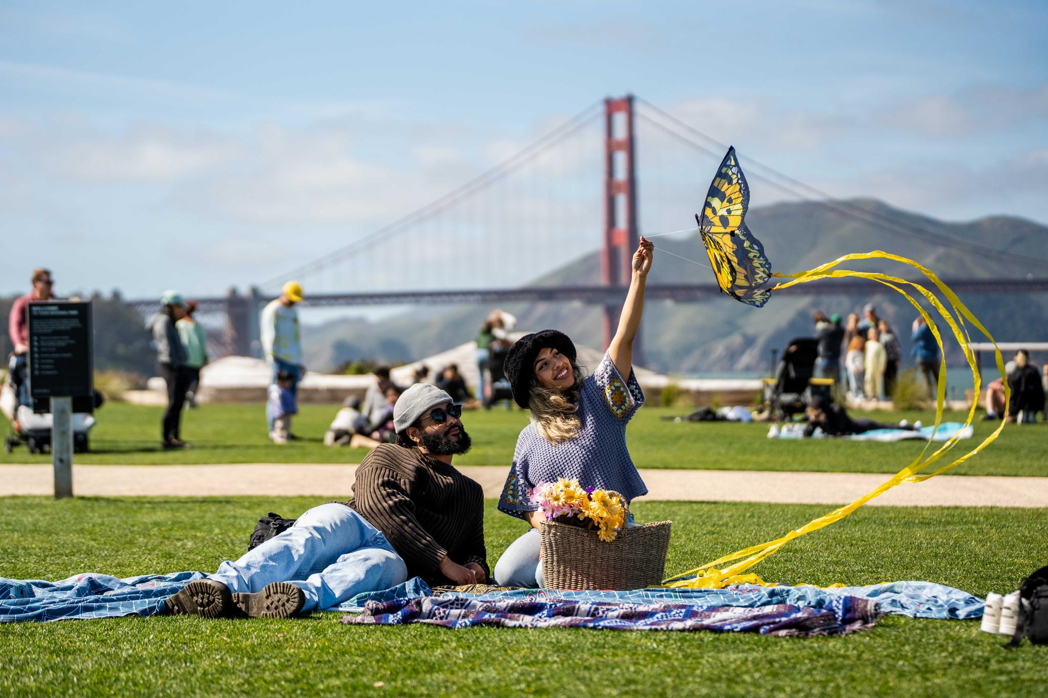 Man and woman sitting on Presidio Tunnel Tops having a picnic with a kite