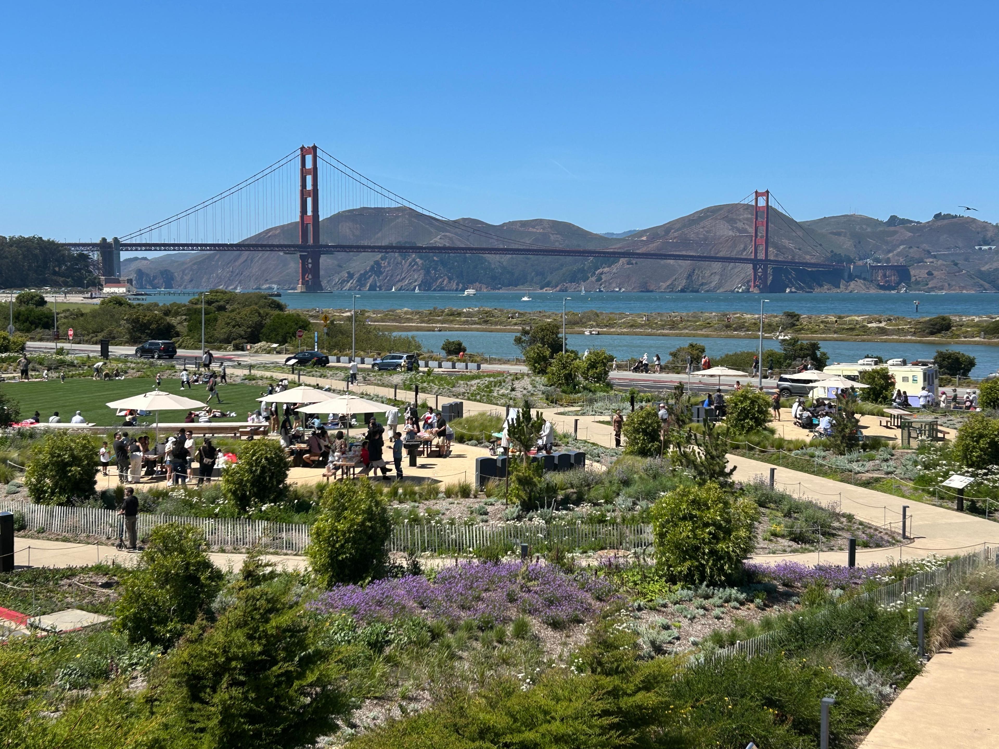 people enjoying Outpost Meadow picnic area looking west with the Golden Gate Bridge in the background