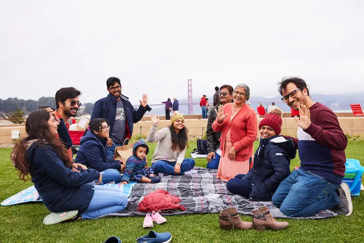 A large group of people having a picnic on a lawn at Presidio Tunnel Tops.