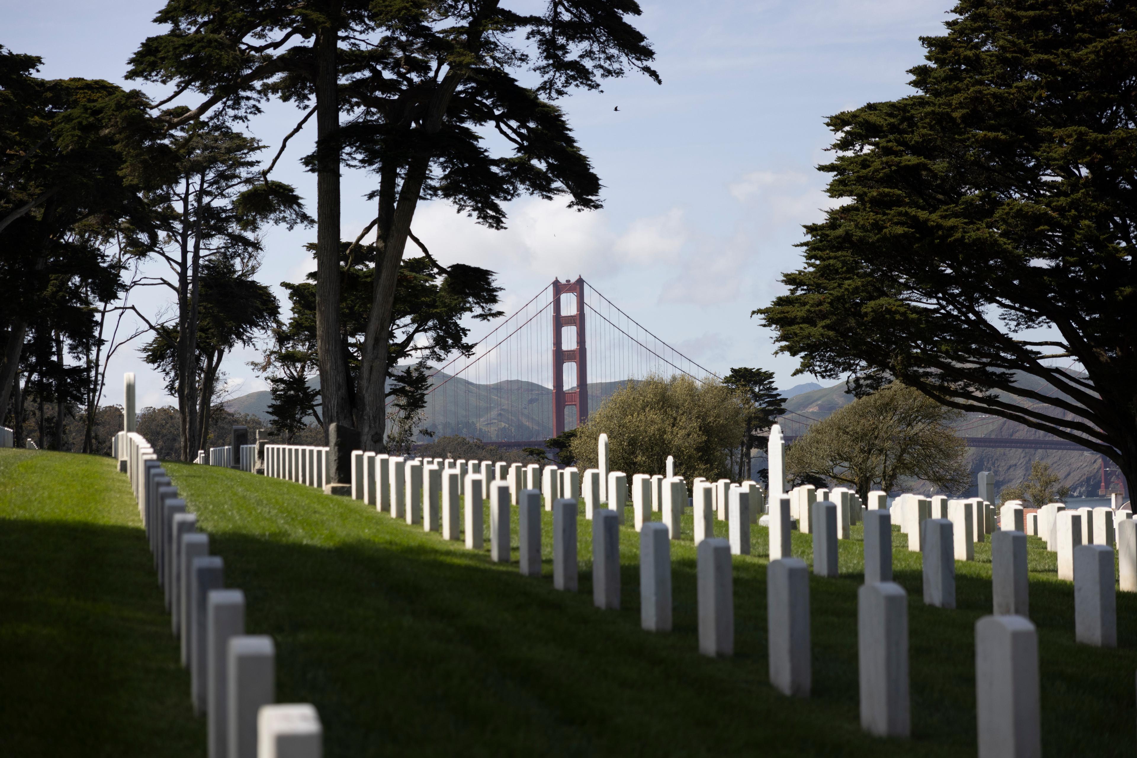 Image of the tombstones on the hill at the San Franciso National Cemetery with the Golden Gate Bridge in the background.