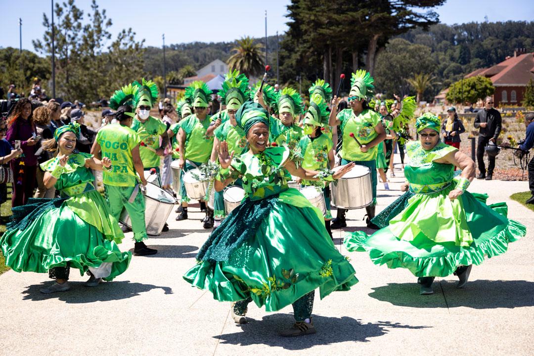Dancers and drummers in green outfits from Fogo Na Roupa in Presidio Tunnel Tops
