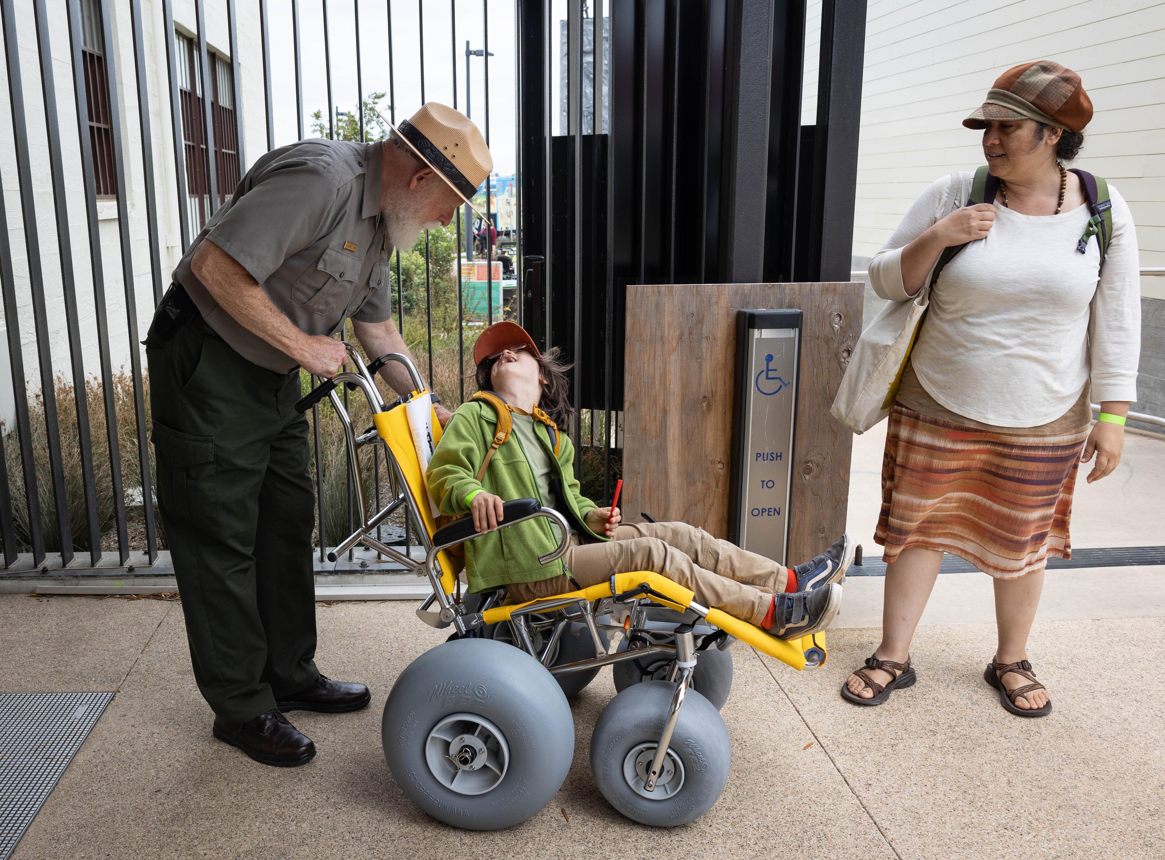 Ranger speaking to a young man in a wheelchair wih his mom standing nearby.