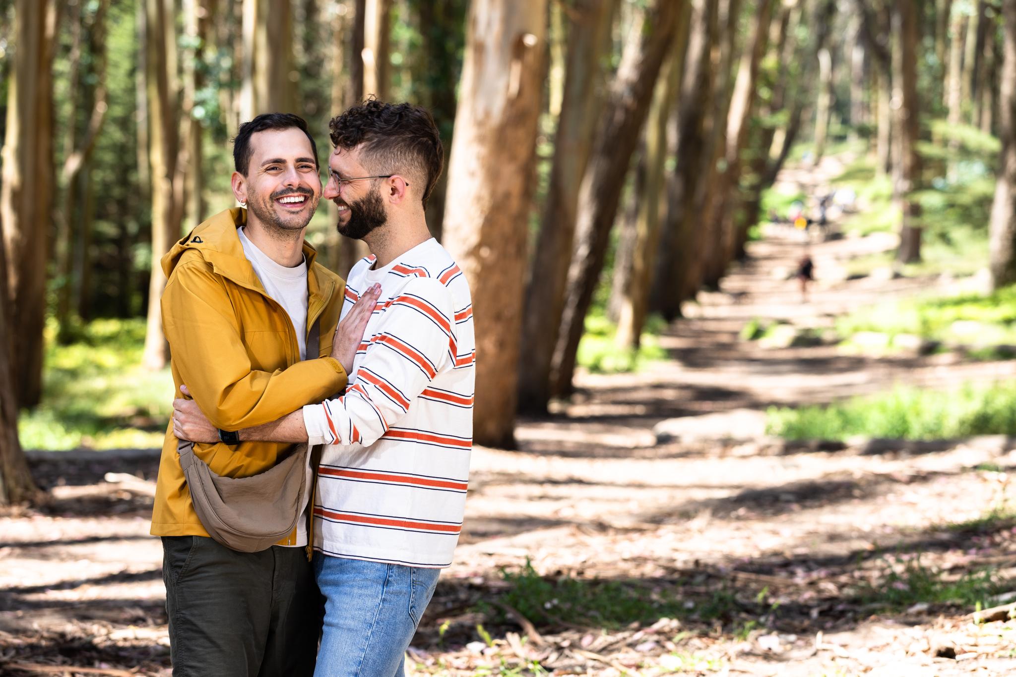 A couple - two men laughing and embracing - in front of Wood Line.