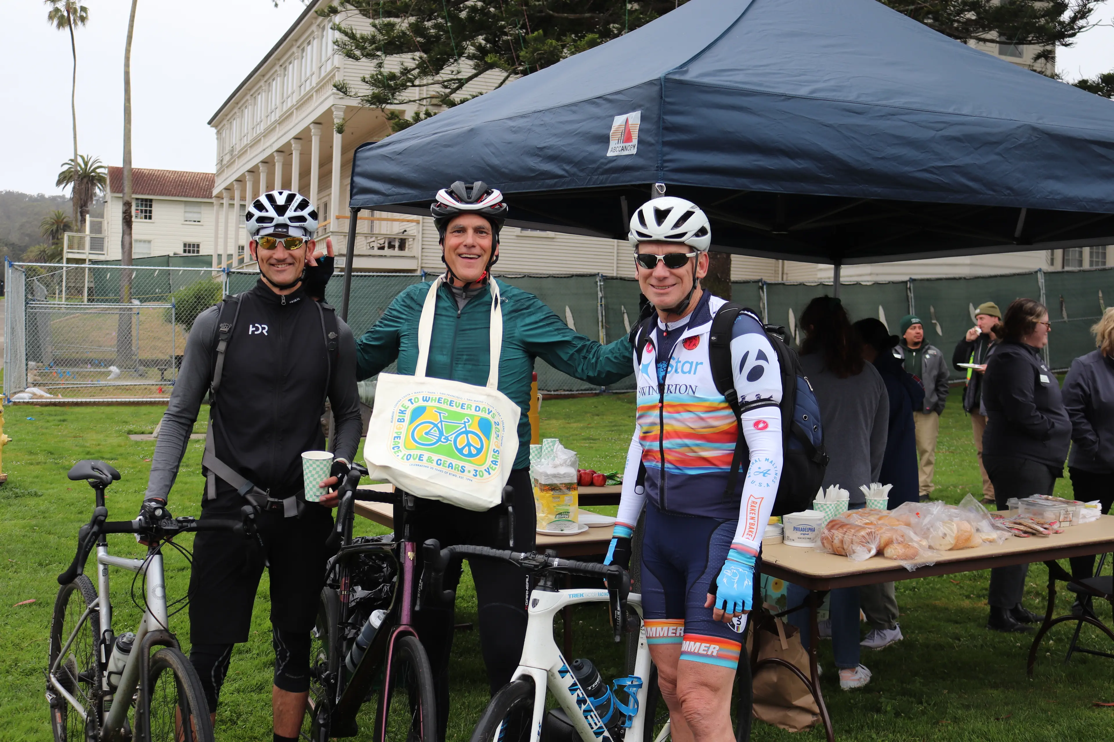 Three men embracing in biking gear for Bike to Anywhere Day