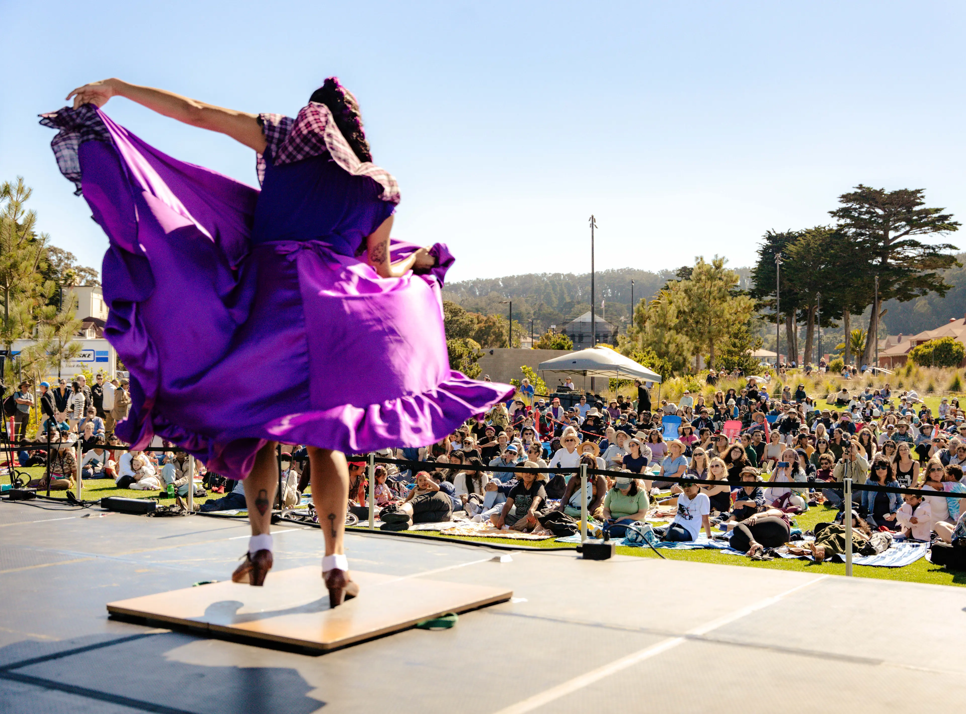 Woman dancing in a purple dress on a stage in the Presidio