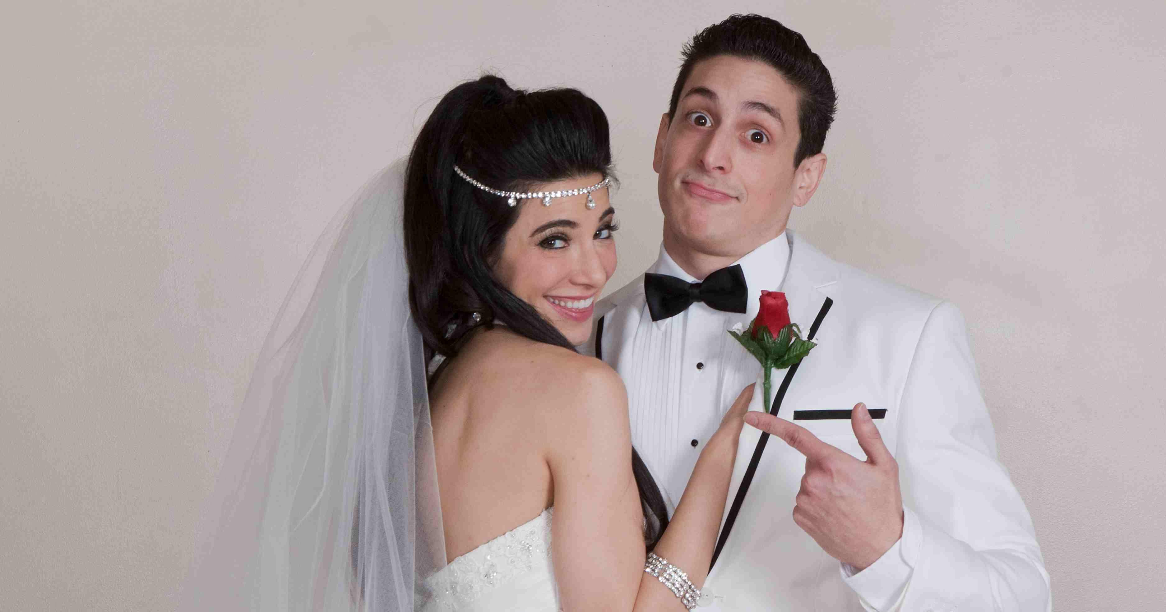 Bride and groom embracing on a white backdrop