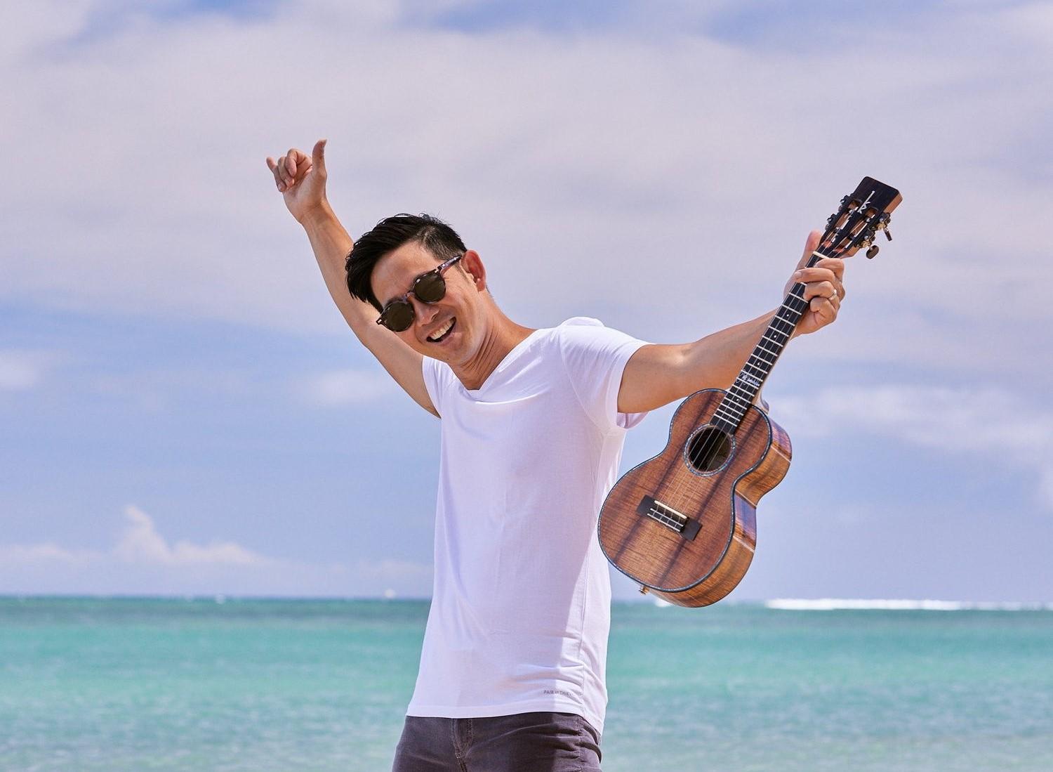 man holding ukelele on a beach