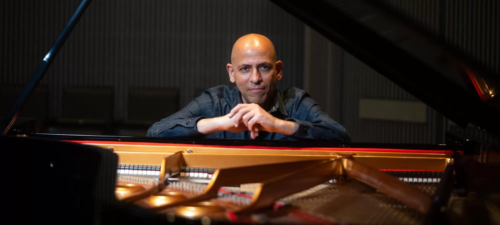 man's solo portrait leaning over an open piano