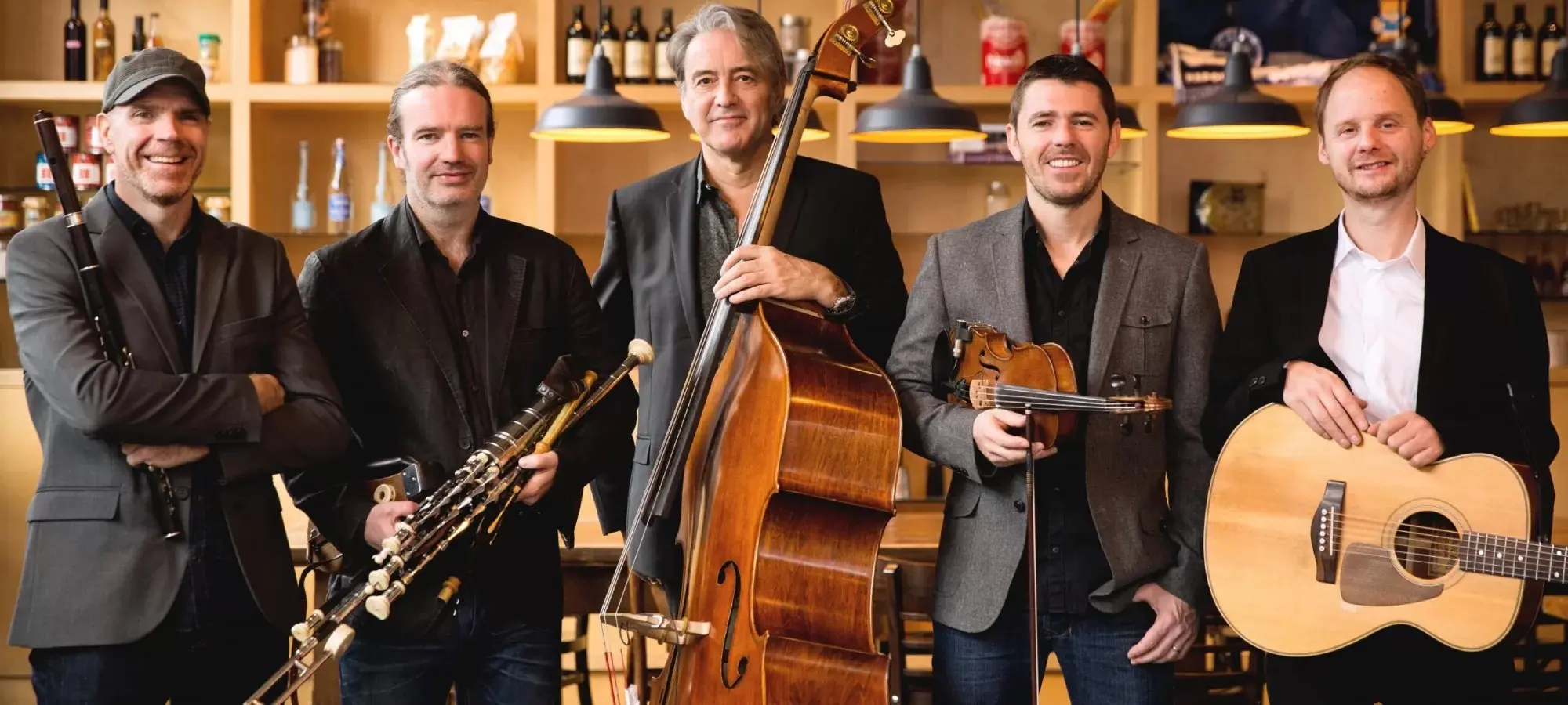 group of five men standing shoulder to shoulder holding their instruments looking at the camera