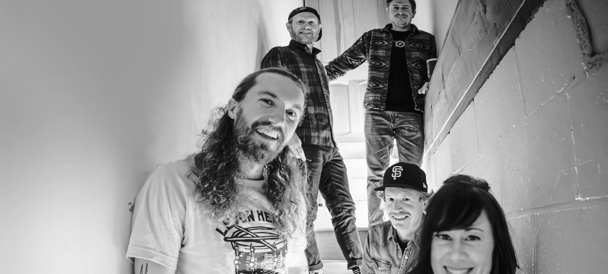 group of four bandmembers standing together in black and white