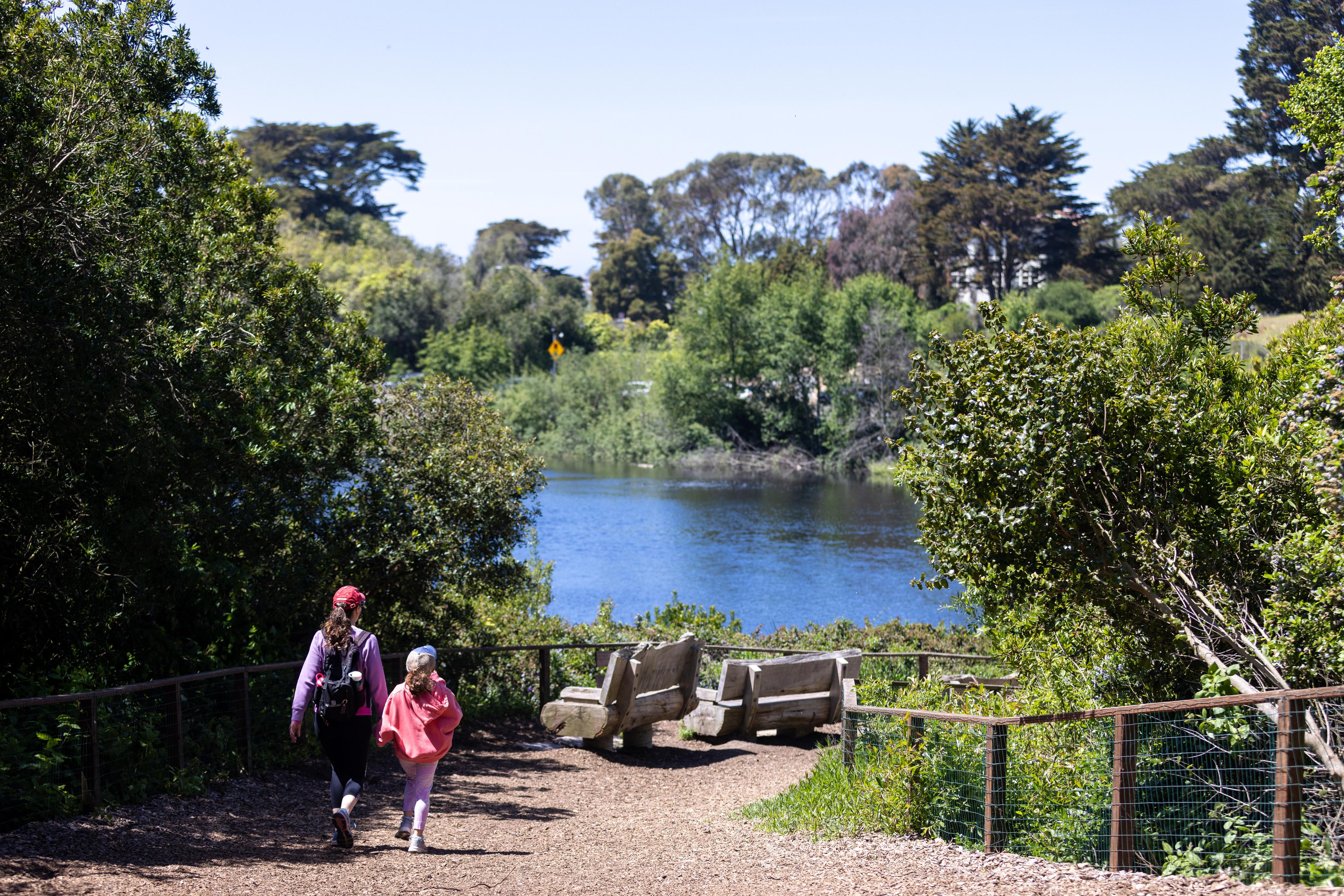 Mother and daughter walking holding hands towards Mountain Lake