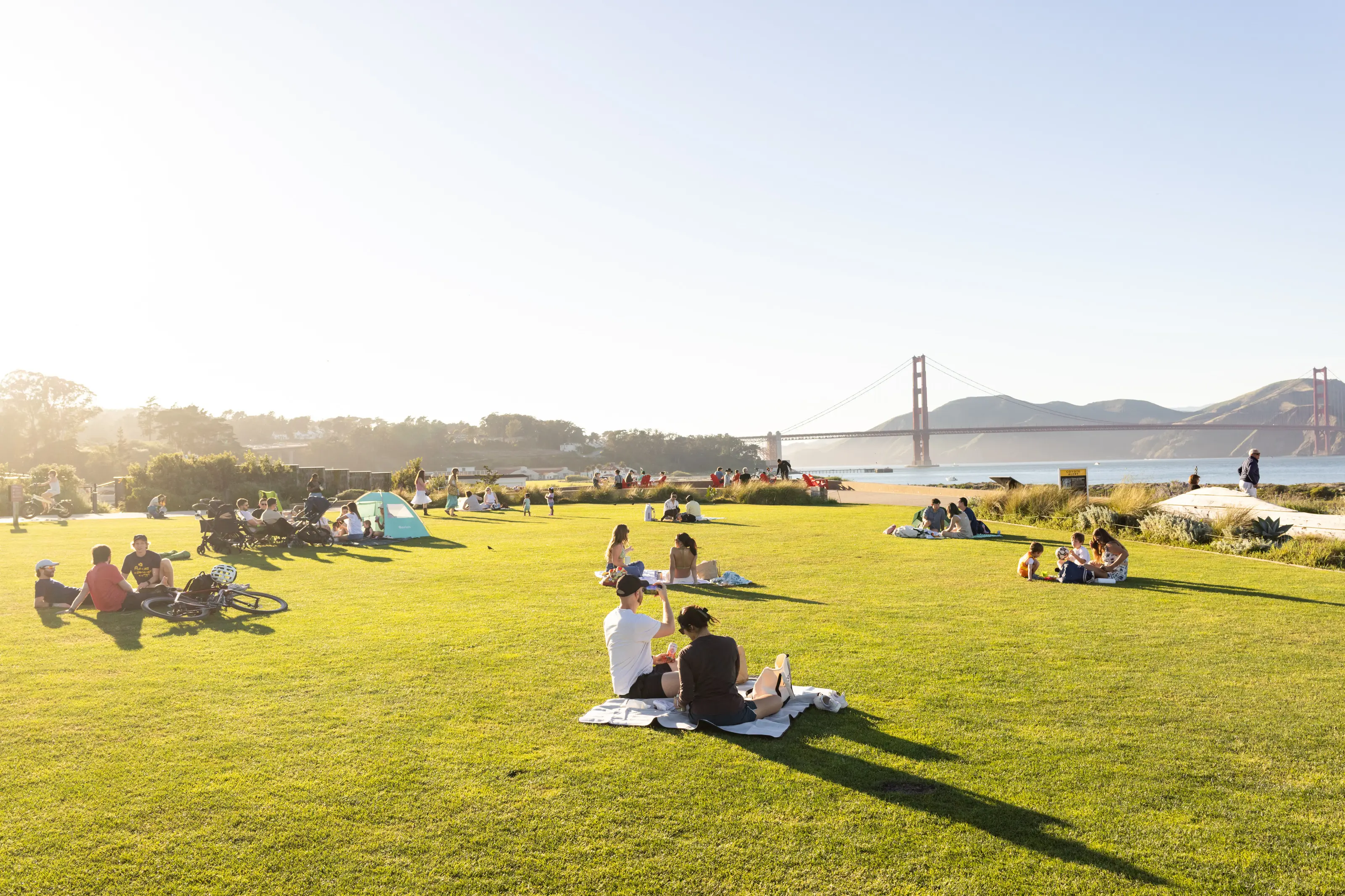 groups of people enjoying the sunshine on Presidio Tunnel Tops with the Golden Gate Bridge in the background