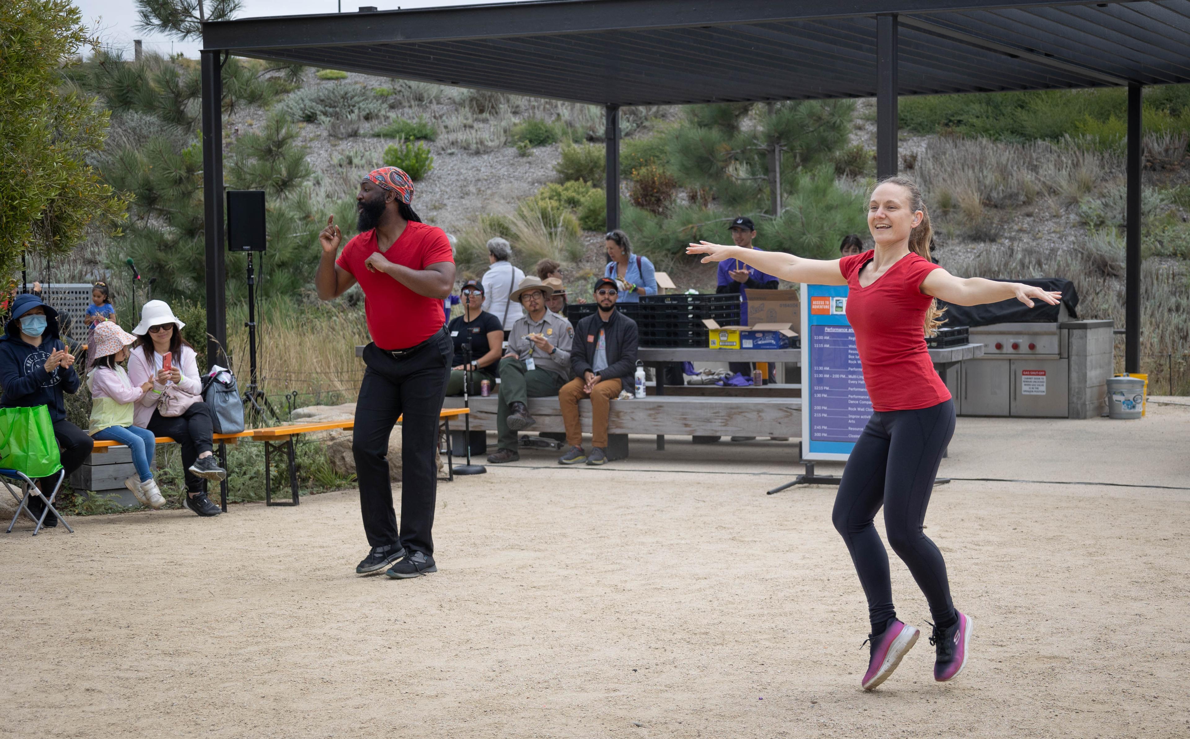 Man and woman wearing red shirt and black pants dancing at the Crissy Field Center