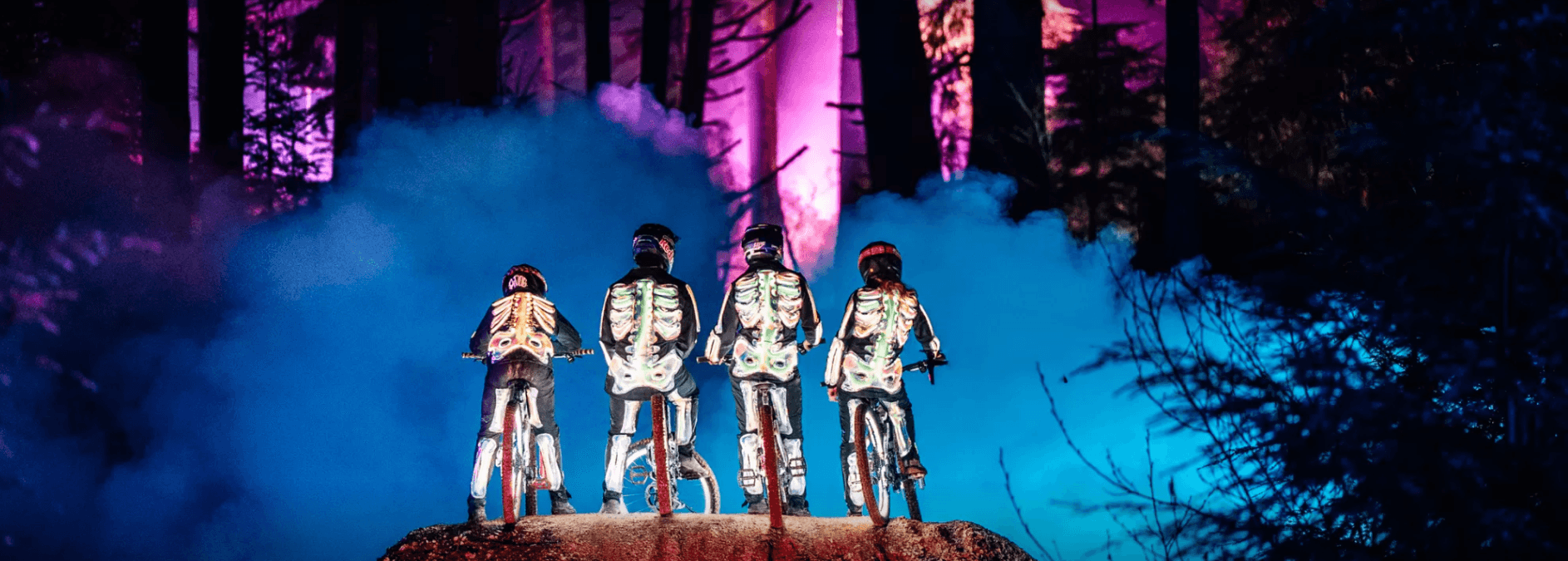 Four people on bikes in light up skeleton suits