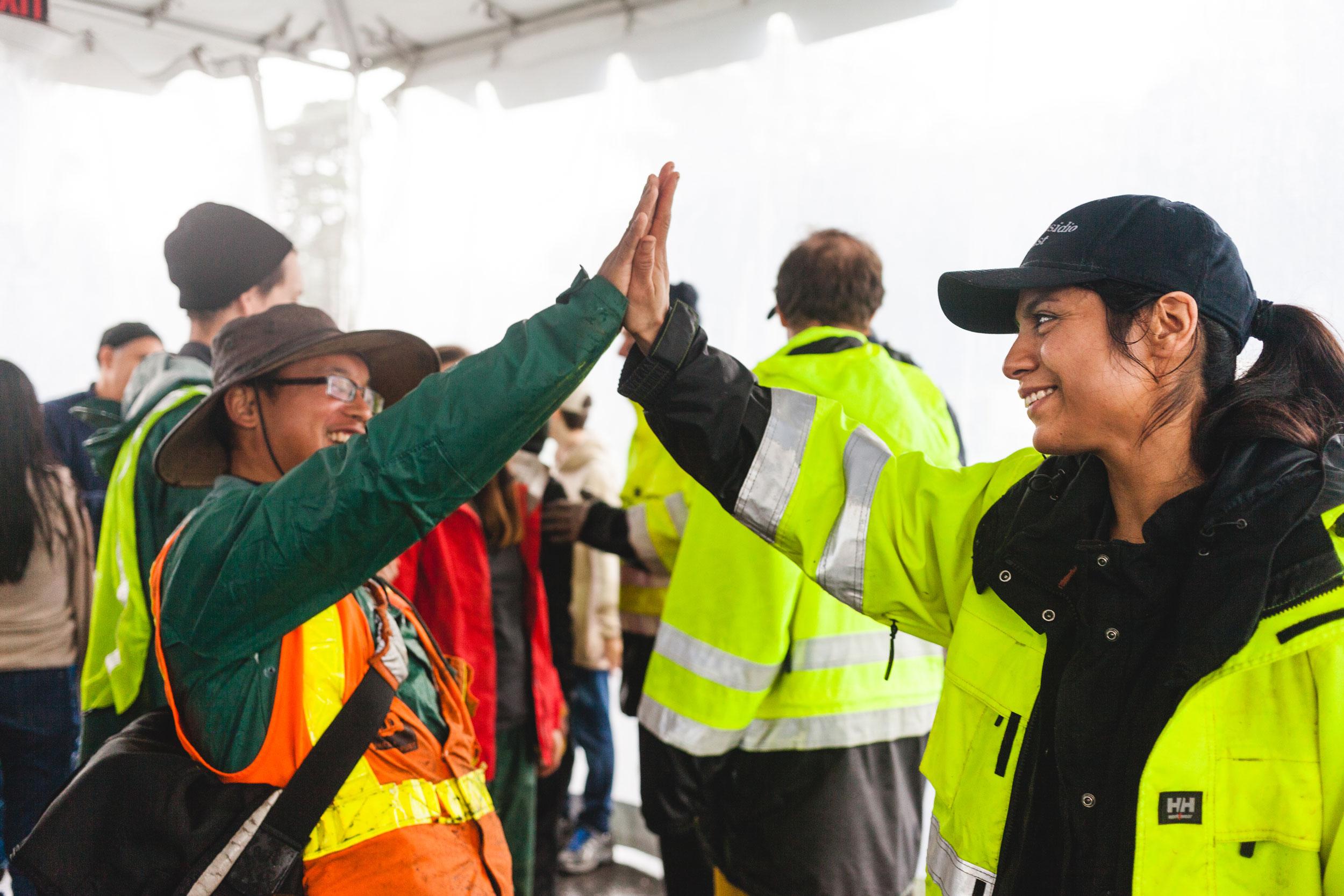 Man and woman in safety vests and jackets high-fiving
