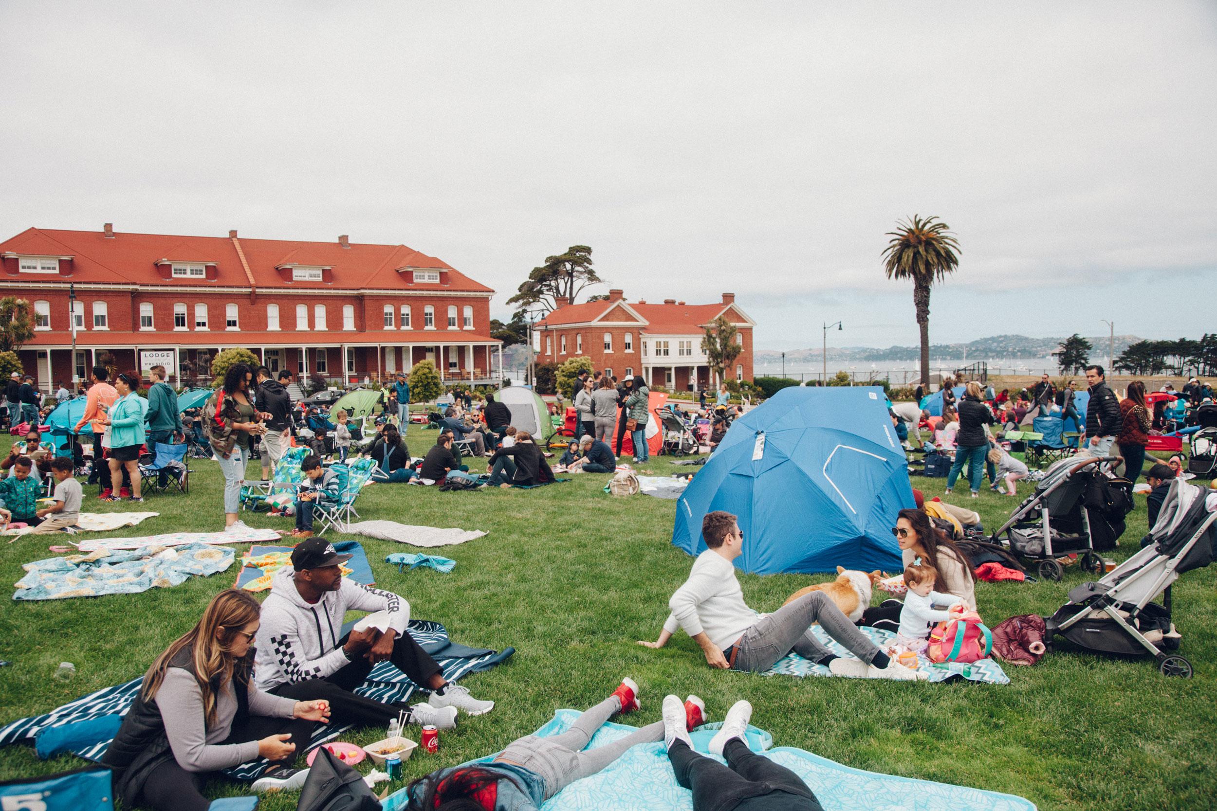 Picnickers with blankets, tents, strollers, chairs on Main Parade Lawn