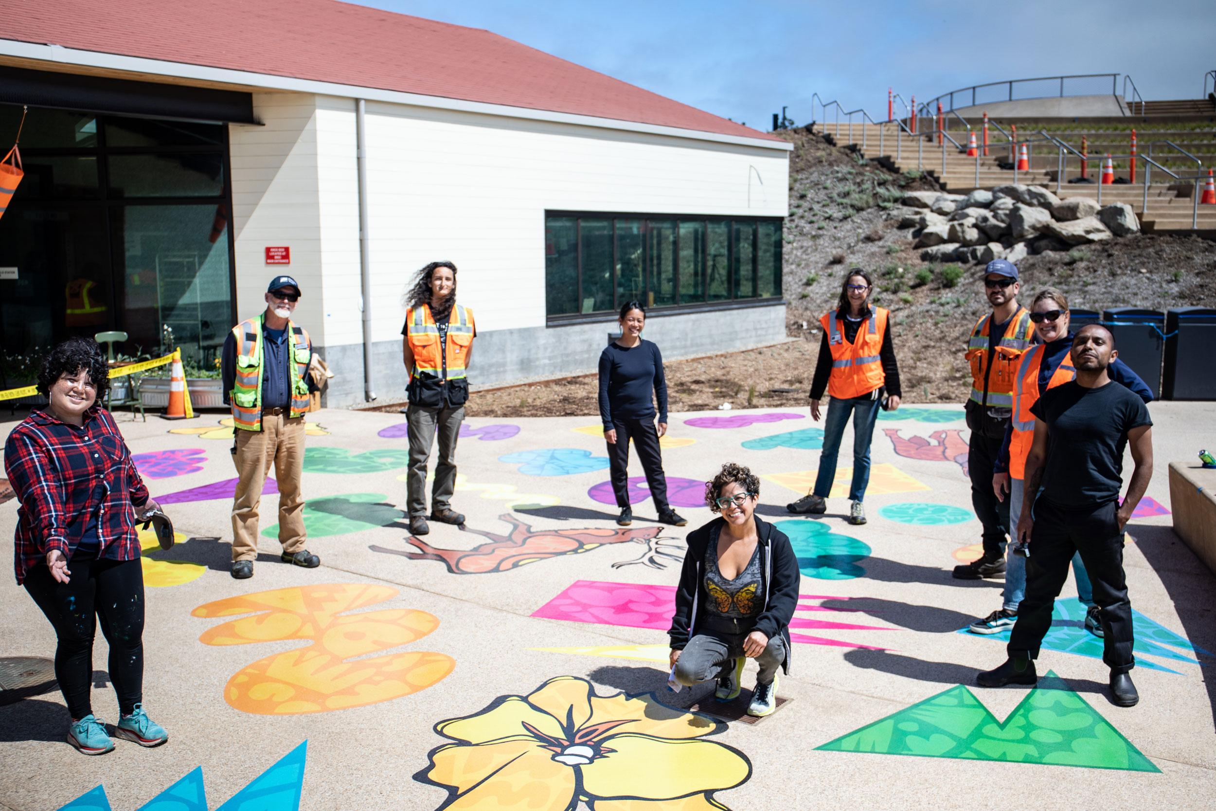 Group photo with Favianna kneeled in the front by her art on ground