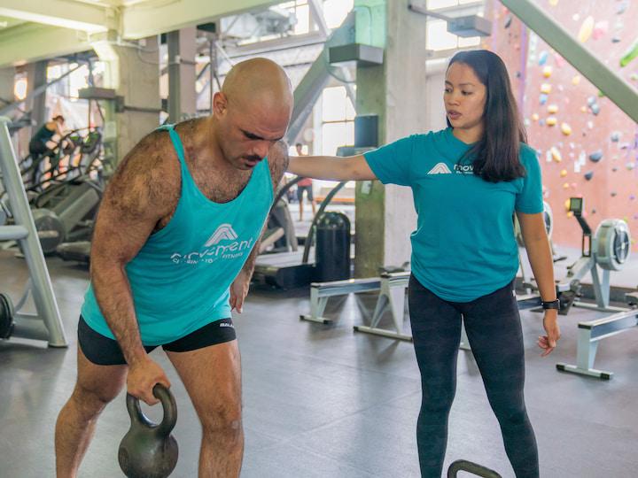 A man lifts weights with a trainer at the Movement gym. Photo courtesy of Movement.