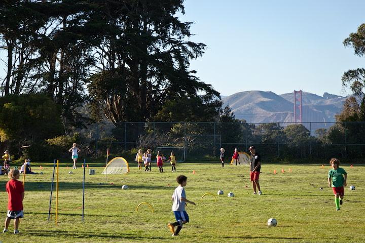 Kids playing soccer on a field at Presidio Wall Playground.