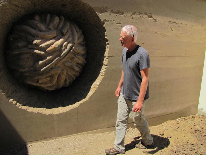 Andy Goldsworthy standing in front of Earth Wall during construction in 2014.