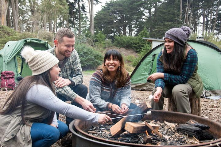 Four people making smores at a fire pit at Rob Hill Campground in the Presidio of San Francisco.