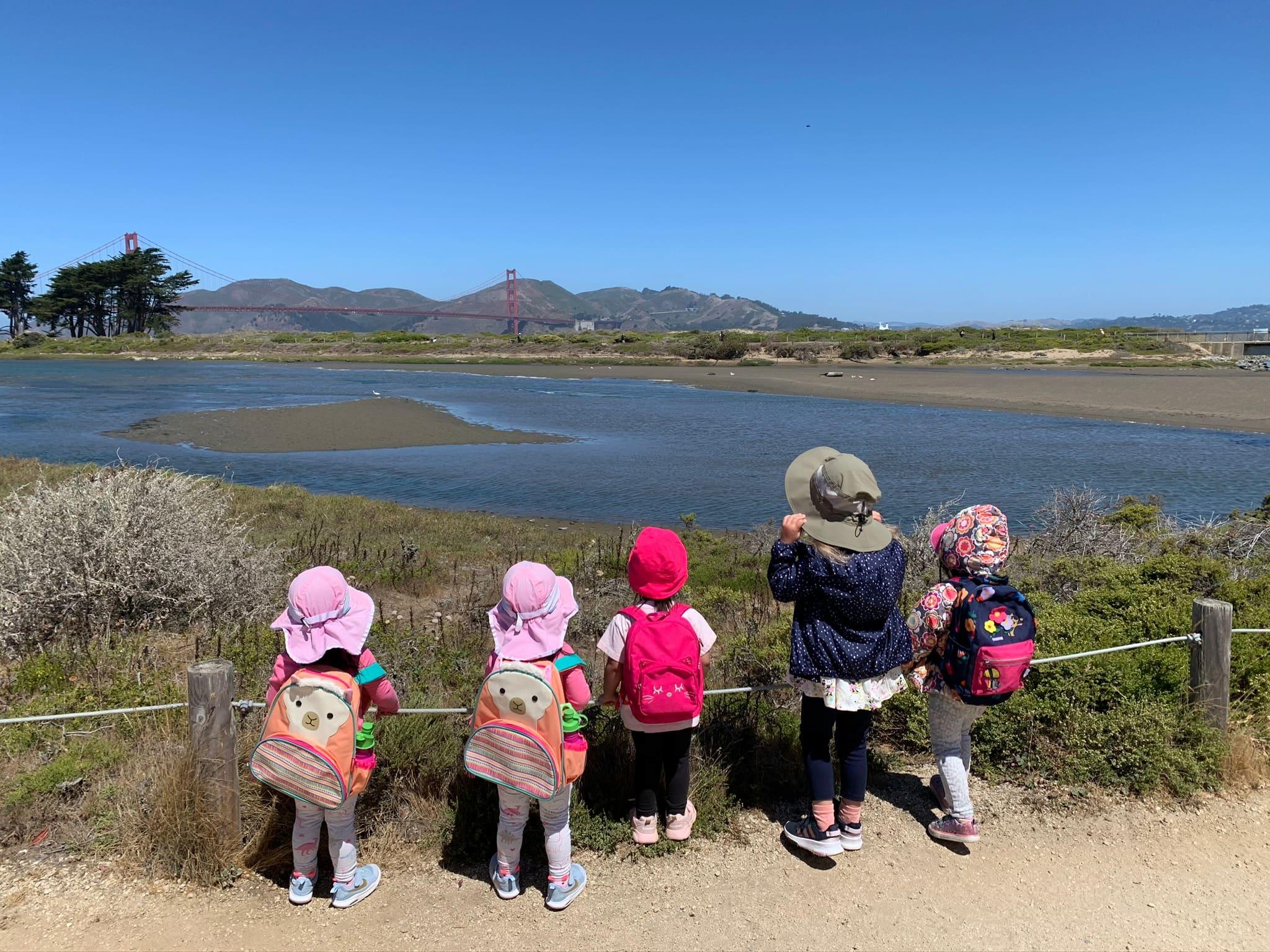 Children looking at Crissy Marsh at the Presidio, with the Golden Gate Bridge in the background. Photo by Little Bee Preschool.