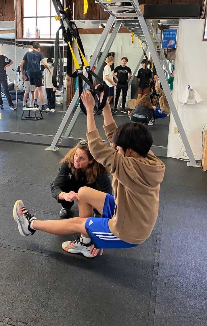 A trainer helping a client with a leg squat. Photo by Lucy Fasano