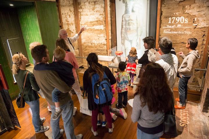 A Presidio volunteer explains Mesa Room exhibits to a group of visitors.