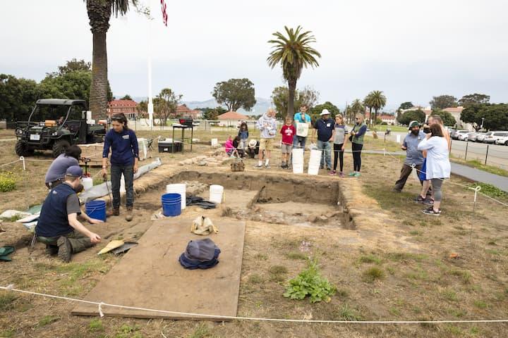Visitors watch an archaeology dig.