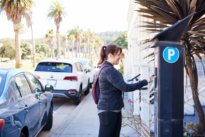 A woman pays for parking at a Pay-and-Display machine.