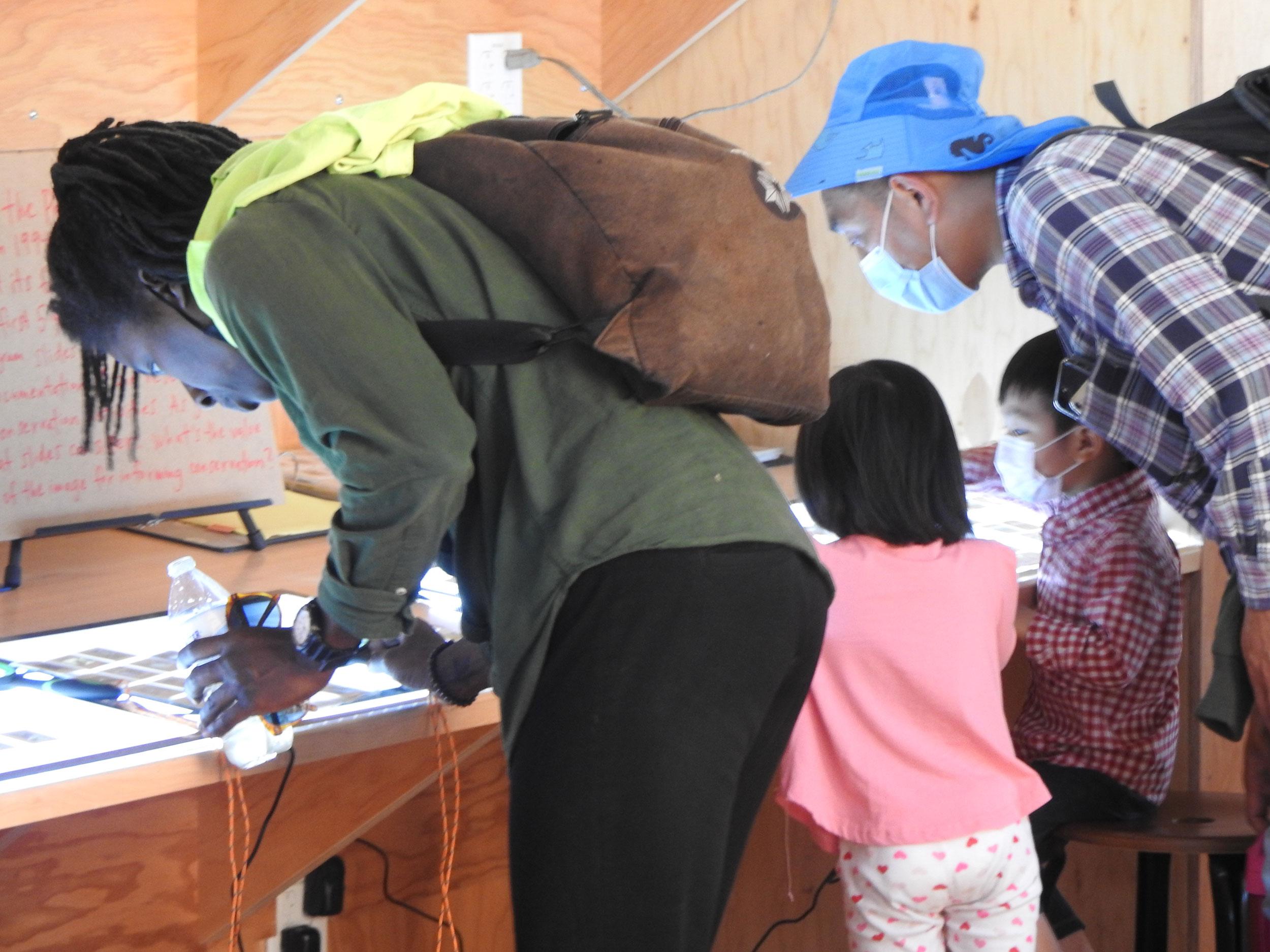 Adults and kids study images at the Field Station.