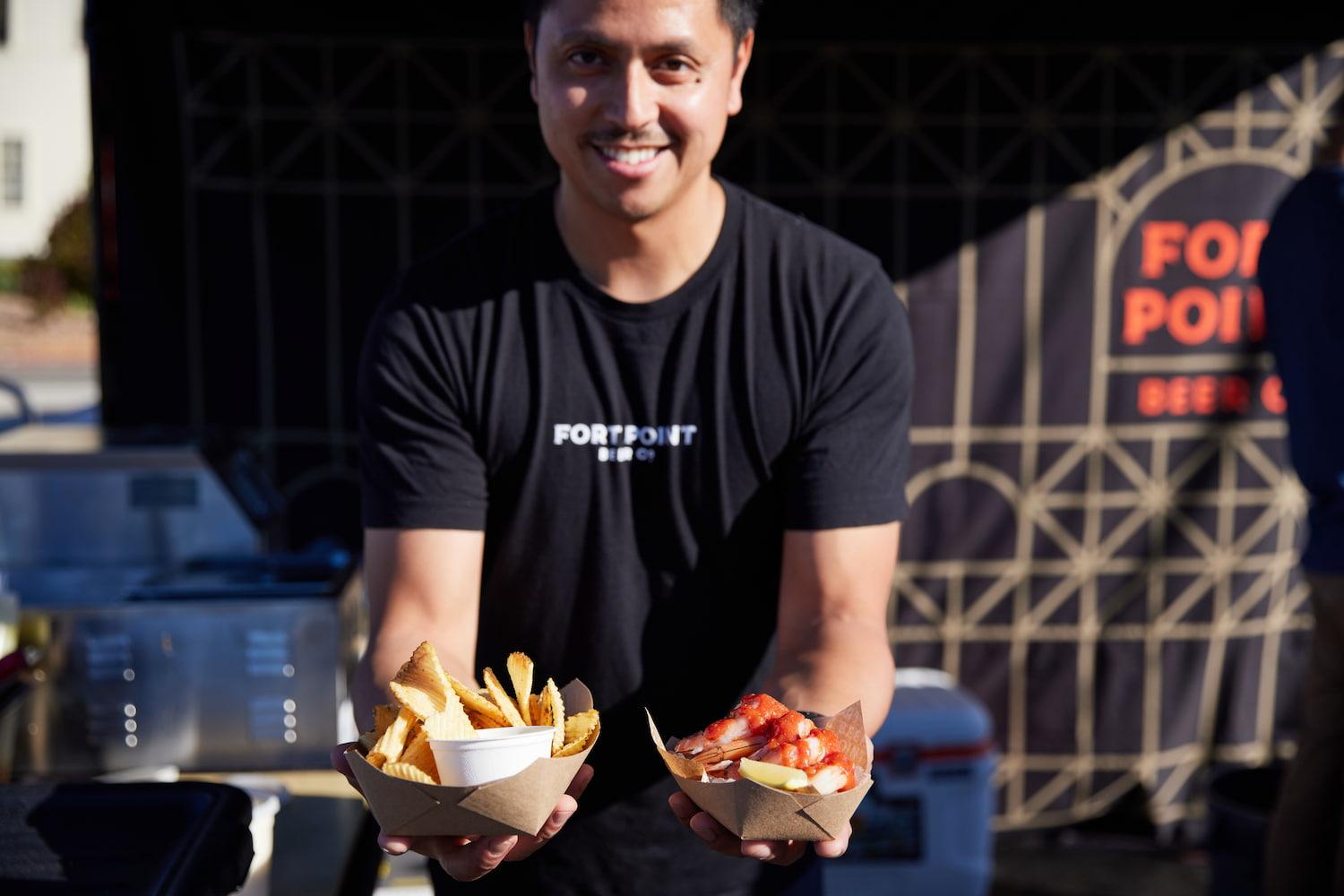 A male food vendor holds two plates of food at Presidio Pop Up. Photo by Rachel Styer.