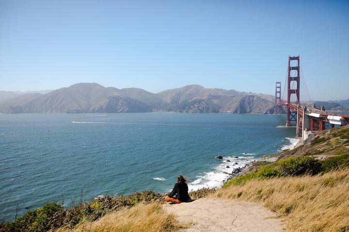 Man sitting while overlooking the Batteries to Bluffs trail with the Golden Gate Bridge in background.