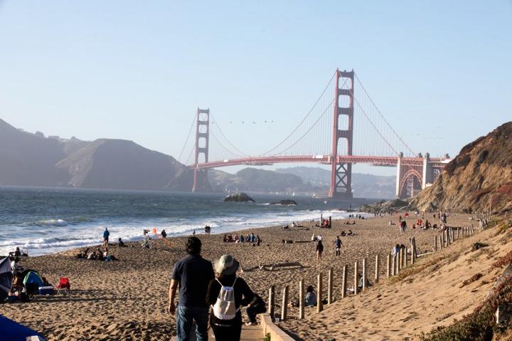 People walking off the trail toward Baker Bridge with views of the Golden Gate Bridge.