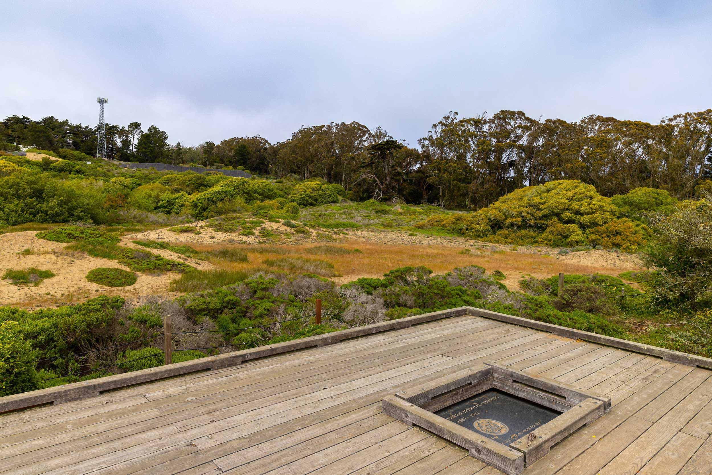 The elevated wooden plaza at the Marine Cemetery Vista in the Presidio, with a plaque and sand dunes. Photo by Myleen Hollero.