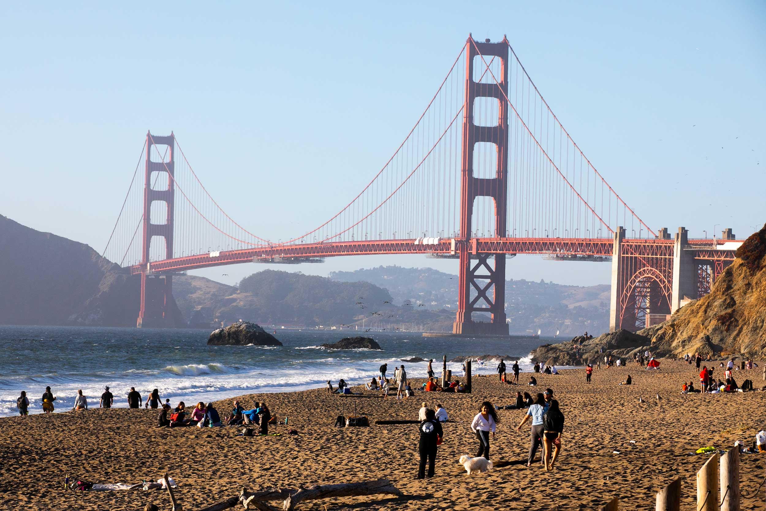 Baker Beach with the Golden Gate Bridge, with visitors on the sand.
