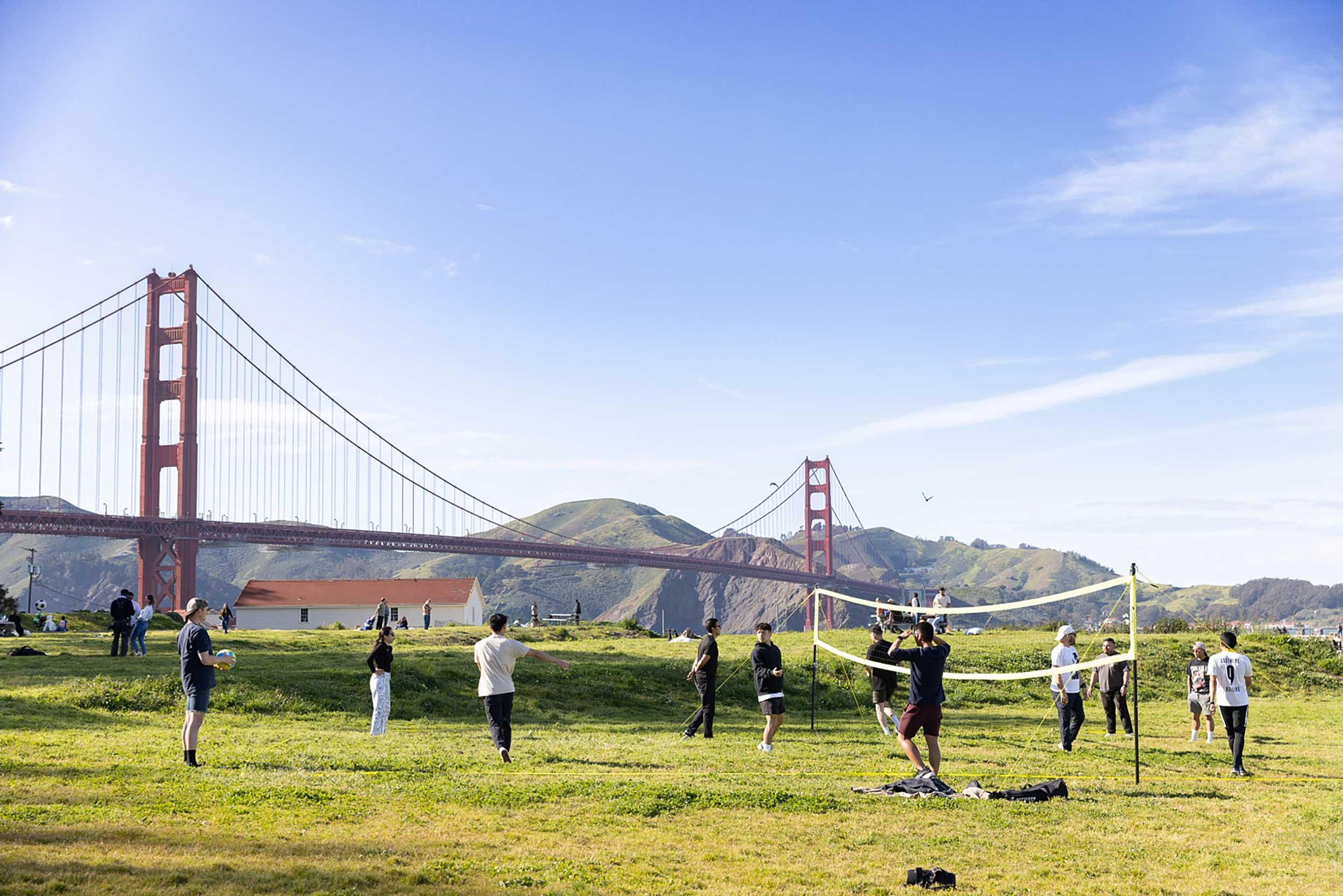 People playing volleyball on the grass at Crissy Field West Bluff with the Golden Gate Bridge in the background Photo by Myleen Hollero.