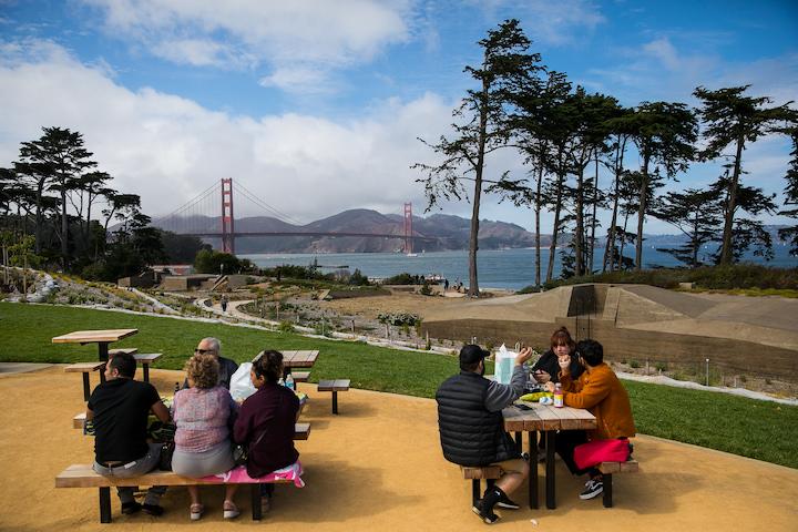 Two groups gather at tables at Battery Bluff, with the Golden Gate Bridge in the background. Photo by Myleen Hollero.