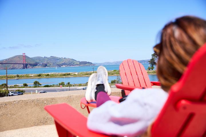 A person sitting in a red chair looking out at the Golden Gate Bridge.