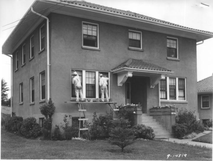 Historic photo from 1937 of two workers repairing a window in a Presidio home.