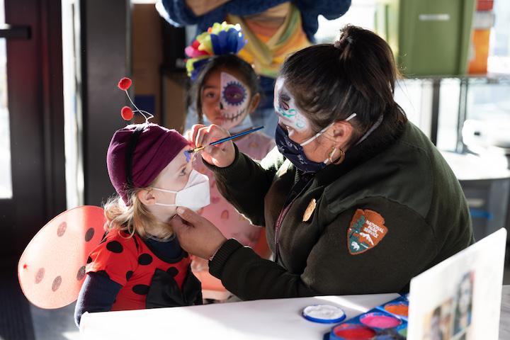 A child gets their face painted during a Dia De Los Muertos celebration at the Presidio.