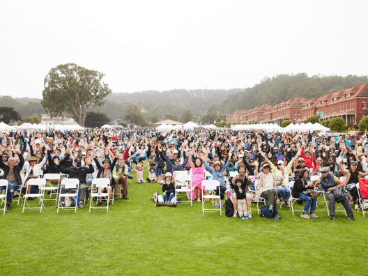 Image of several people sitting at an outdoor event.