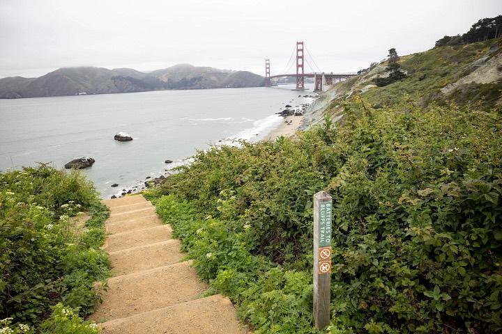 Batteries to Bluffs trail with steps and sign-post and Golden Gate Bridge in the background.