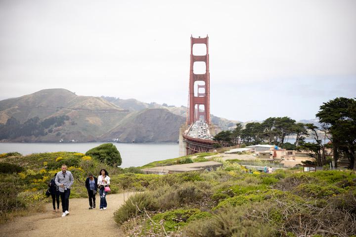 People on the Coastal Trail near the batteries and Golden Gate Overlook with Golden Gate Bridge in the background.