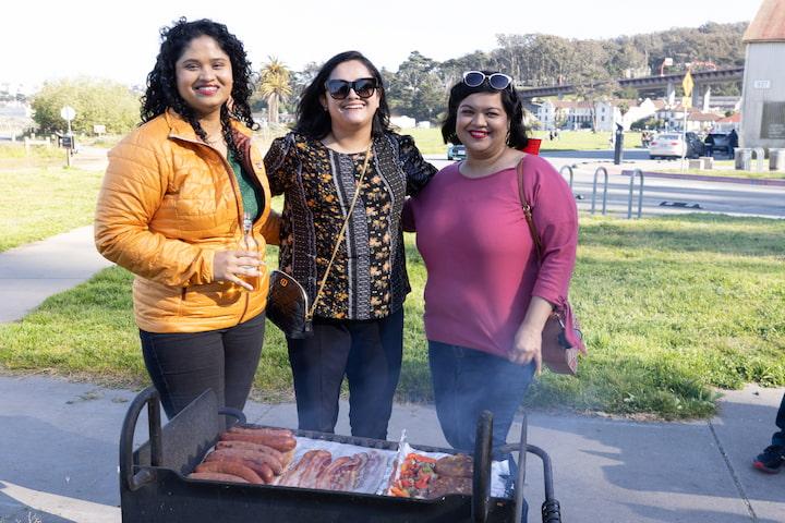 Three women at a barbeque grill at Crissy Field West Bluff Picnic Area.